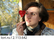 Симпатичная девушка смотрит на леденец в форме сердце. Стоковое фото, фотограф Вера Тропынина / Фотобанк Лори