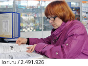 Пенсионерка на почте листает подписной каталог (2011 год). Редакционное фото, фотограф Анна Мартынова / Фотобанк Лори