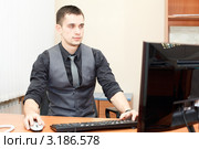 Мужчина за столом в офисе работает на компьютере. Стоковое фото, фотограф Кекяляйнен Андрей / Фотобанк Лори