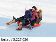 Две радостные девочки и мальчик едут на тюбинге с горки (2012 год). Редакционное фото, фотограф Игорь Низов / Фотобанк Лори
