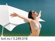 Счастливая девушка в белом бикини стоит на пляже, раскинув руки в стороны. Стоковое фото, фотограф CandyBox Images / Фотобанк Лори