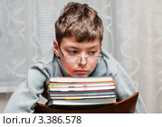 Задумчивый мальчик сидит на стуле  со стопкой книг. Стоковое фото, фотограф Игорь Низов / Фотобанк Лори