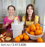Две женщины отжимают апельсиновый сок на кухне. Стоковое фото, фотограф Яков Филимонов / Фотобанк Лори