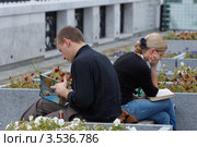 Молодая пара читает на уличной скамейке (2009 год). Редакционное фото, фотограф Юрий Синицын / Фотобанк Лори