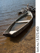 Деревянная лодка у берега, на половину наполненная водой (2012 год). Редакционное фото, фотограф Андрей Петраковский / Фотобанк Лори