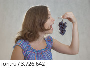 Девочка с виноградной гроздью на сером фоне. Стоковое фото, фотограф Матвеева Наталья / Фотобанк Лори