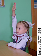 Первоклассница тянет руку, сидя за партой в классе. Стоковое фото, фотограф Илюхина Наталья / Фотобанк Лори
