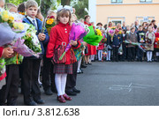 Первоклассница с цветами стоит среди ребят на школьной линейке 1 сентября (2012 год). Редакционное фото, фотограф Кекяляйнен Андрей / Фотобанк Лори