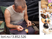 Сорочинская ярмарка. Мужчина разукрашивает поделки. (2012 год). Редакционное фото, фотограф Олег Голиков / Фотобанк Лори