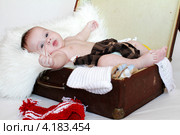 Спокойный малыш лежит в чемодане с одеждой (3,5 месяца) Стоковое фото, фотограф ivolodina / Фотобанк Лори