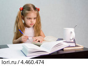 Девочка листает книгу и пишет на листе бумаги конспект сидя за столом. Стоковое фото, фотограф Иванов Алексей / Фотобанк Лори
