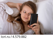 Девушка читает сообщение, лежа на кровати. Фокус на телефоне. Стоковое фото, фотограф Дегтярева Виктория / Фотобанк Лори