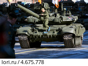 Водитель в бахилах идет по танку Т-90 «Владимир», стоящий на Тверской улице города Москвы, перед генеральной репетицией Парада Победы на Красной площади (2013 год). Редакционное фото, фотограф Николай Винокуров / Фотобанк Лори