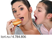 Девочка хочет откусить пончик, который ест мама. Стоковое фото, фотограф Phovoir Images / Фотобанк Лори