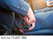 Водитель в деловом костюме за рулём автомобиля, пристёгивается ремнём безопасности. Стоковое фото, фотограф Константин Лабунский / Фотобанк Лори