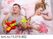 Пара в постели: муж играет на гитаре, жена спит. Стоковое фото, фотограф Иванов Алексей / Фотобанк Лори