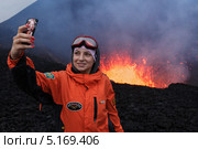 Девушка-турист фотографируется на фоне извержения вулкана Плоский Толбачик на Камчатке (2013 год). Редакционное фото, фотограф А. А. Пирагис / Фотобанк Лори