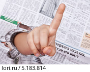 Социум и дети. Детская рука в газетной дыре показывает предупреждающий знак внимание. (2013 год). Редакционное фото, фотограф Элина Гаревская / Фотобанк Лори