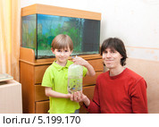 Папа с ребенком и пакетом с рыбками на фоне домашнего аквариума. Стоковое фото, фотограф Юлия Кузнецова / Фотобанк Лори