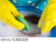 Руки в резиновых желтых перчатках моют посуду в пластиковом тазу с мыльной водой. Стоковое фото, фотограф Ольга Марк / Фотобанк Лори