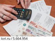 Женщина рассчитывает на калькуляторе семейный бюджет на коммунальные расходы (2014 год). Редакционное фото, фотограф Игорь Низов / Фотобанк Лори