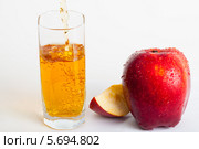Рядом со спелым яблоком стоит стакан, который наполняется соком. Стоковое фото, фотограф Сергей Дубров / Фотобанк Лори