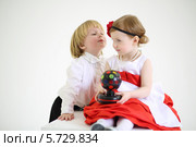 Маленький мальчик тянется, чтобы поцеловать девочку в нарядном платье. Стоковое фото, фотограф Losevsky Pavel / Фотобанк Лори