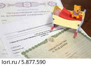 Свидетельство о рождении, уведомление о выдаче государственного сертификата на материнский капитал, государственный сертификат на материнский капитал, игрушечная младенческая кроватка. Стоковое фото, фотограф Юлия Ухина / Фотобанк Лори
