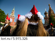 Девочка в красной пилотке и с большими белыми бантами Спасской башни московского Кремля перед началом торжественной линейки, посвященной Дню пионерии и приему в пионеры на Красной площади города Москвы (2014 год). Редакционное фото, фотограф Николай Винокуров / Фотобанк Лори