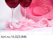 Два бокала вина рядом с розовым нижним бельем и шляпой на белом фоне. Стоковое фото, фотограф Владимир Ходатаев / Фотобанк Лори