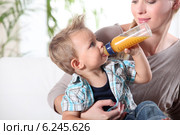 Child drinking juice in his mother's lap. Стоковое фото, фотограф Phovoir Images / Фотобанк Лори