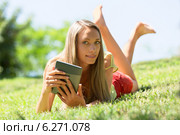 girl lying on grass enjoying reading ereader. Стоковое фото, фотограф Яков Филимонов / Фотобанк Лори
