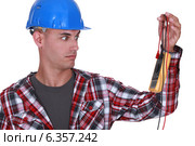 Wide-eyed tradesman staring at a multimeter. Стоковое фото, фотограф Phovoir Images / Фотобанк Лори
