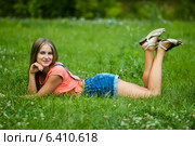 Красивая девушка лежит на зелёной траве подняв ноги вверх. Стоковое фото, фотограф Игорь Низов / Фотобанк Лори