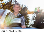 Пожилой мужчина стоит рядом с автомобилем в лучах солнца. Стоковое фото, фотограф Кекяляйнен Андрей / Фотобанк Лори
