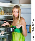 Woman holding foul food near fridge. Стоковое фото, фотограф Яков Филимонов / Фотобанк Лори