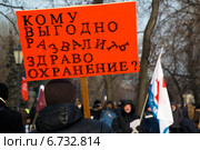 Митинг против реформы здравоохранения, закрытия больниц и сокращения рабочих мест. Мужчина держит баннер с надписью "Кому выгодно развалить здравоохранение?" в центре города Москвы, Россия, 30 ноября 2014. Редакционное фото, фотограф Николай Винокуров / Фотобанк Лори