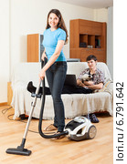 Girl doing floor cleaning while man resting over sofa. Стоковое фото, фотограф Яков Филимонов / Фотобанк Лори