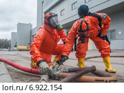 Бойцы пожарной охраны в костюме химзащиты регулируют подачу воды во время учений на промышленном объекте (2013 год). Редакционное фото, фотограф Сайганов Александр / Фотобанк Лори