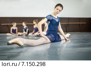Молодая балерина занимается на полу в классе хореографии. Стоковое фото, фотограф Andriy Bezuglov / Фотобанк Лори