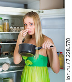 Woman holding foul food near fridge. Стоковое фото, фотограф Яков Филимонов / Фотобанк Лори