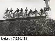 Девять молодых людей сидят на каменных буквах при въезде в город  Экибастуз 1970 год (2015 год). Редакционное фото, фотограф Emelinna / Фотобанк Лори