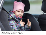 Девочка, пристегнутая в автомобильном кресле показывает большие пальцы вверх. Стоковое фото, фотограф Кекяляйнен Андрей / Фотобанк Лори