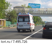 Автомобиль скорой помощи едет на вызов по встречной полосе шоссе на фоне пешеходного моста (2015 год). Редакционное фото, фотограф SevenOne / Фотобанк Лори