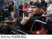 Почитатель творчества Виктора Цоя в инвалидном кресле у стены на улице Арбат в центре города Москвы на собрании в память в 25-летнего юбилея со дня гибели певца, Россия (2015 год). Редакционное фото, фотограф Николай Винокуров / Фотобанк Лори
