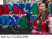 Прохожие стоят у надписи "Яркие люди" во время карнавального шествия фестиваля на Неглинной улице в праздник День города Москвы, Россия (2015 год). Редакционное фото, фотограф Николай Винокуров / Фотобанк Лори