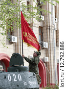 Волгоград, мужчина закрепляет красный флаг дивизии на танке Т34, перед Парадом Победы 9 мая (2015 год). Редакционное фото, фотограф Дмитрий Неумоин / Фотобанк Лори