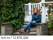 Симпатичная девушка сидит на деревянных ступенях загородного дома. Стоковое фото, фотограф Игорь Низов / Фотобанк Лори