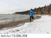 Мужчина в синей куртке бежит по снегу на берегу реки. Стоковое фото, фотограф Наталия Макарова / Фотобанк Лори