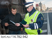 Автоинспектор ДПС проверяет документы у водителя грузового автомобиля на городской улице (2013 год). Редакционное фото, фотограф Михаил Михин / Фотобанк Лори